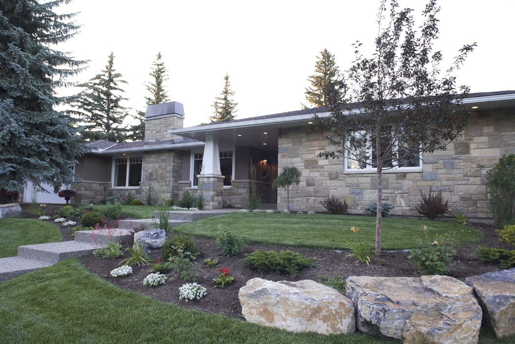 A house with stone walls and a large rock garden.