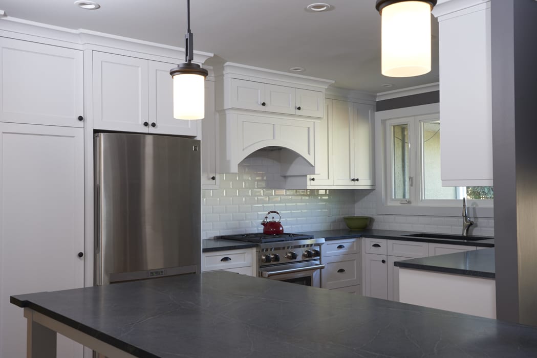 A kitchen with white cabinets and black counter tops.