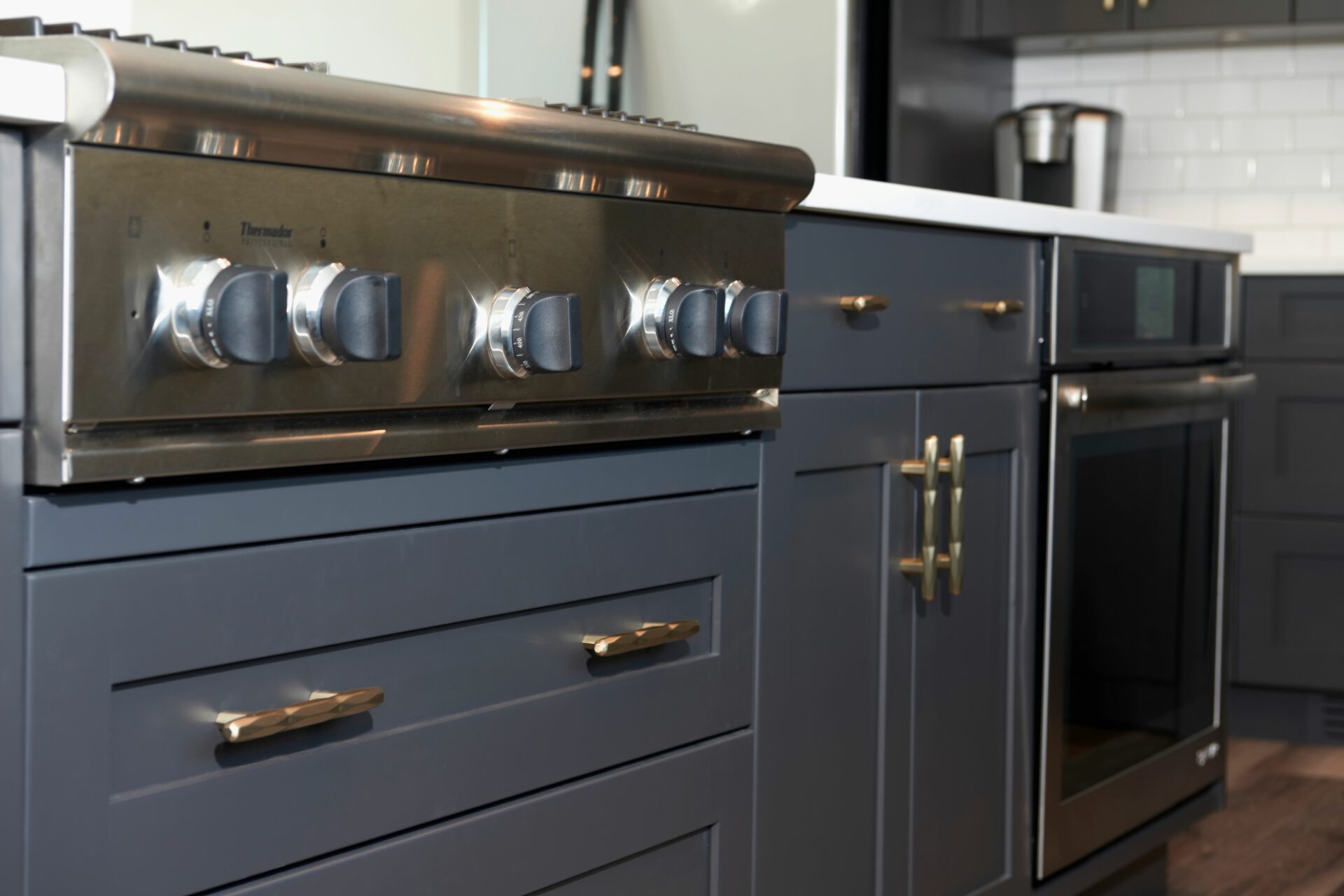A kitchen with black cabinets and gold hardware.